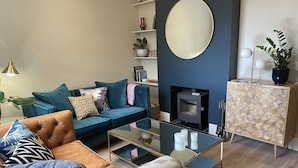 Ein modernes Wohnzimmer mit Sofa, Couchtisch, Kamin und Schrank.