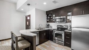 A modern kitchen with dark cabinets, stainless steel appliances, a built-in microwave, and a large refrigerator. - Oceanfront Luxury at Hilton Oceanaire Resort – Two Stunning Oceanview Balconies! (Virginia Beach)