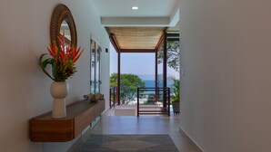 A modern hallway with a wooden console table, a large mirror, and a potted plant.