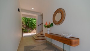 A modern hallway with a wooden console table, a mirror, and a staircase leading to a garden.