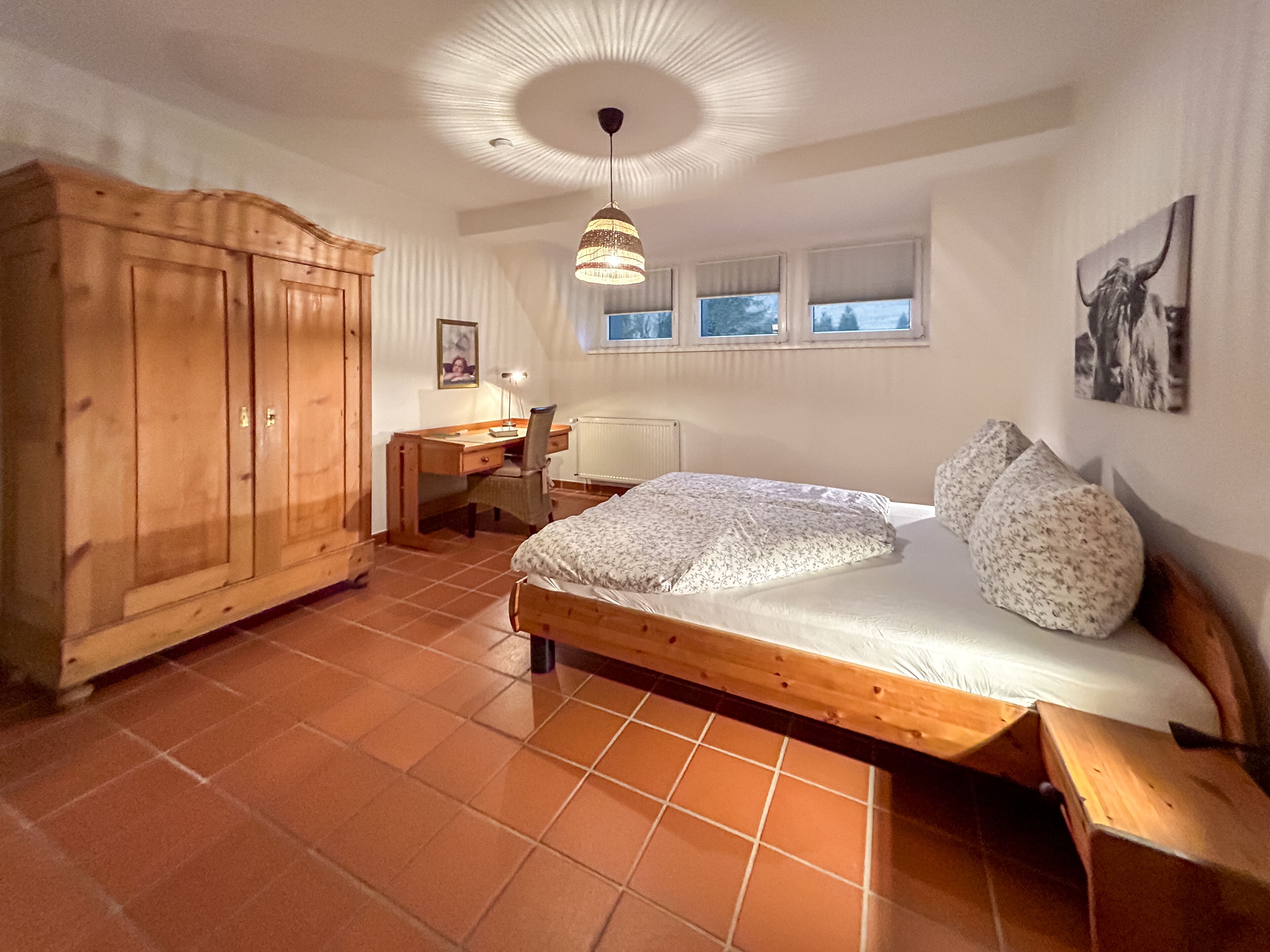 A bedroom with a wooden bed, a desk, and a wardrobe.