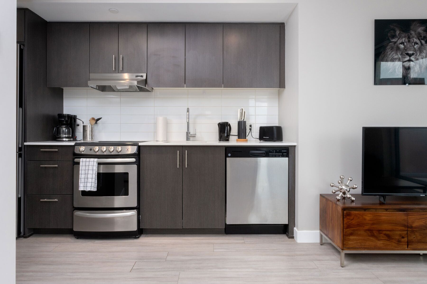 Una cocina moderna con armarios oscuros, electrodomésticos de acero inoxidable y un aparador de madera.