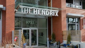 A building with a glass entrance and the name "THE HENDRIX" displayed above. - Corporate Stays Hendrix Aparments (Edmonton)