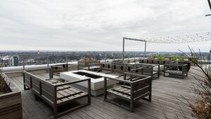 A rooftop terrace with wooden flooring, several seating areas, and a view of the cityscape. - Corporate Stays Hendrix Aparments (Edmonton)