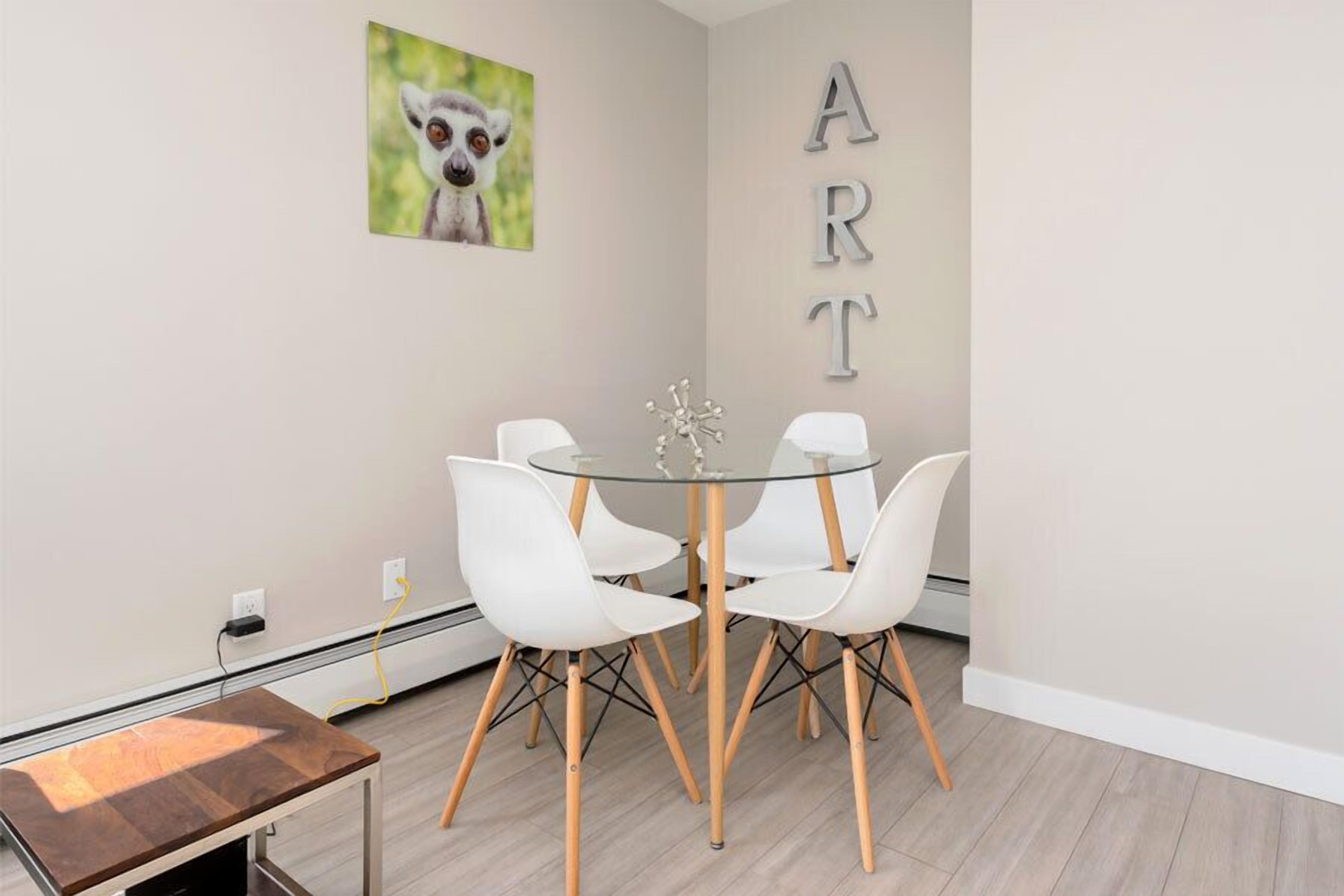 A modern dining area with a glass table, white chairs, and a wooden bench.