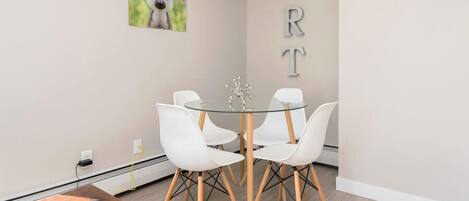 A modern dining area with a glass table, white chairs, and a wooden bench.