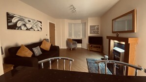A living room with a sofa, a television, a fireplace, and a staircase. - 2 Guests - 5min To The Beach - Fireplace (Scarborough)