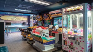 Une salle d’arcade intérieure proposant divers jeux, notamment un jeu sur le thème de « Kawasaki » et un jeu de grue appelé « Xtra Play ».