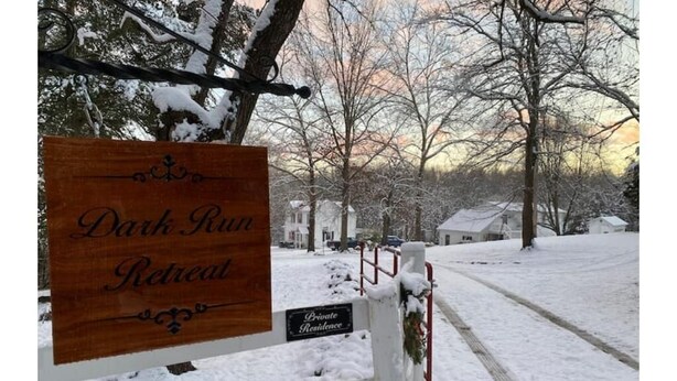 A wooden sign for a Dark Run Retreat with a 'Private Residence' sign below it, set against a snowy landscape with bare trees and a house in the background. - The Studio at Dark Run Retreat (Madison)