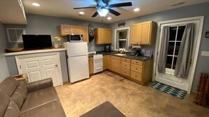 A compact kitchen with a ceiling fan, wooden cabinets, a refrigerator, and a microwave. - The Studio at Dark Run Retreat (Madison)