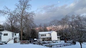 A residential area with two houses, a snow-covered lawn, and leafless trees. - The Studio at Dark Run Retreat (Madison)
