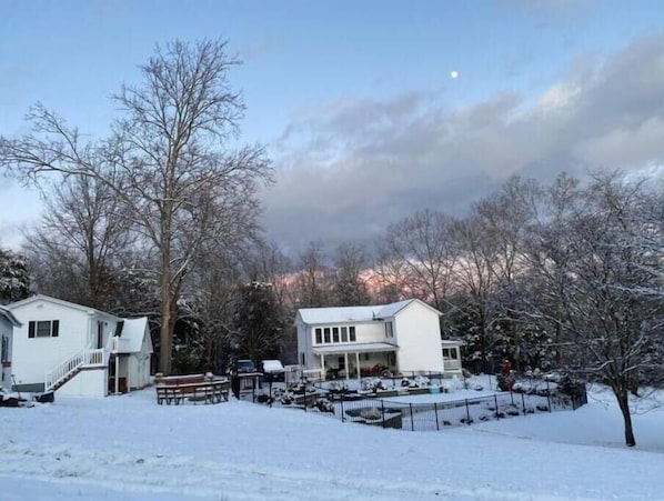 Ein Wohngebiet mit zwei Häusern, einem mit Schnee bedeckten Rasen und kahl stehenden Bäumen.