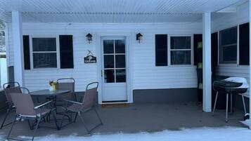 Guests can enter or exit through this cozy outdoor area featuring a small table and chairs under a covered porch.
