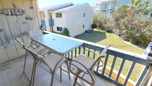 Ein Balkon mit Tisch und Stühlen, Blick auf ein Gebäude und etwas Grün.