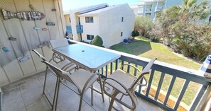 Un balcone con tavolo e sedie, vista su un edificio e presenza di piante.