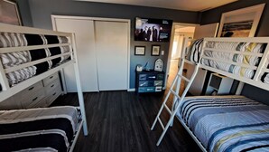 Ein Zimmer mit Etagenbetten, einem Fernseher und einem kleinen Schreibtisch mit Schubladen.