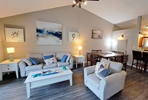 A modern living room with a sofa, armchair, coffee table, and dining area. - 1503 Beachy-2Bd-2Bth Beach Service Included - 2 Chairs and Umbrella (Destin)