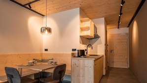 A compact kitchen with a wooden island, a dining area with a table and chairs, and a visible door leading to another room. - Holiday apartment Ammerglück "Classic" in Oberammergau (Oberammergau)