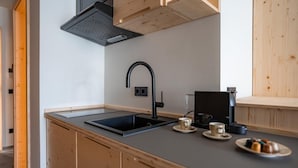 A compact kitchen with a black sink, wooden cabinets, and a coffee machine. - Holiday apartment Ammerglück "Classic" in Oberammergau (Oberammergau)