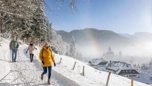 Un sendero cubierto de nieve, una valla rústica, un edificio con cúpula y cielo despejado.