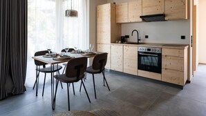 A modern kitchen with wooden cabinets, a built-in oven, and a dining area with a table and chairs.
