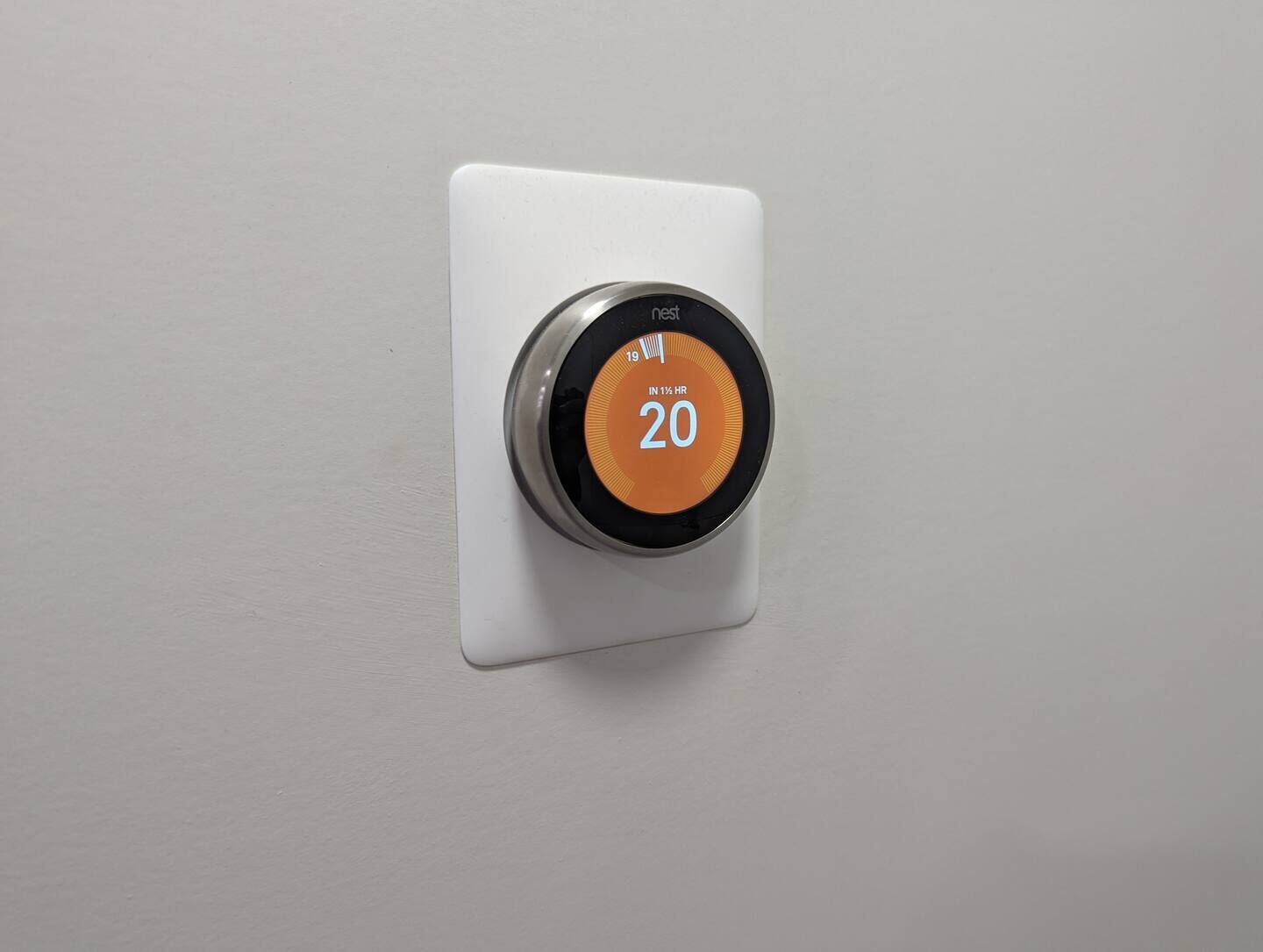 A thermostat with a digital display showing the temperature as 20 degrees.