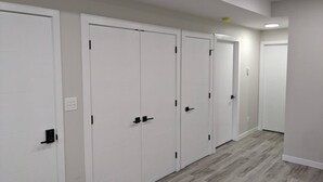 A hallway with white doors and a light wood floor. - Confortable brand-new 1-bedroom close to downtown
(Saskatoon)
