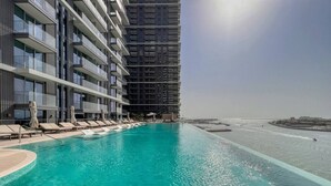 A swimming pool with lounge chairs and a view of the sea. - Sea view 2BR Beach Isle (Dubai)