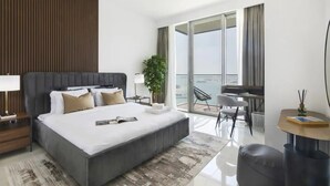 A modern hotel room with a large bed, a desk, and a balcony with a view of the sea. - Sea view 2BR Beach Isle (Dubai)