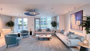A modern living room with a sofa set, armchairs, a coffee table, and two potted plants. - Sea view 2BR Beach Isle (Dubai)