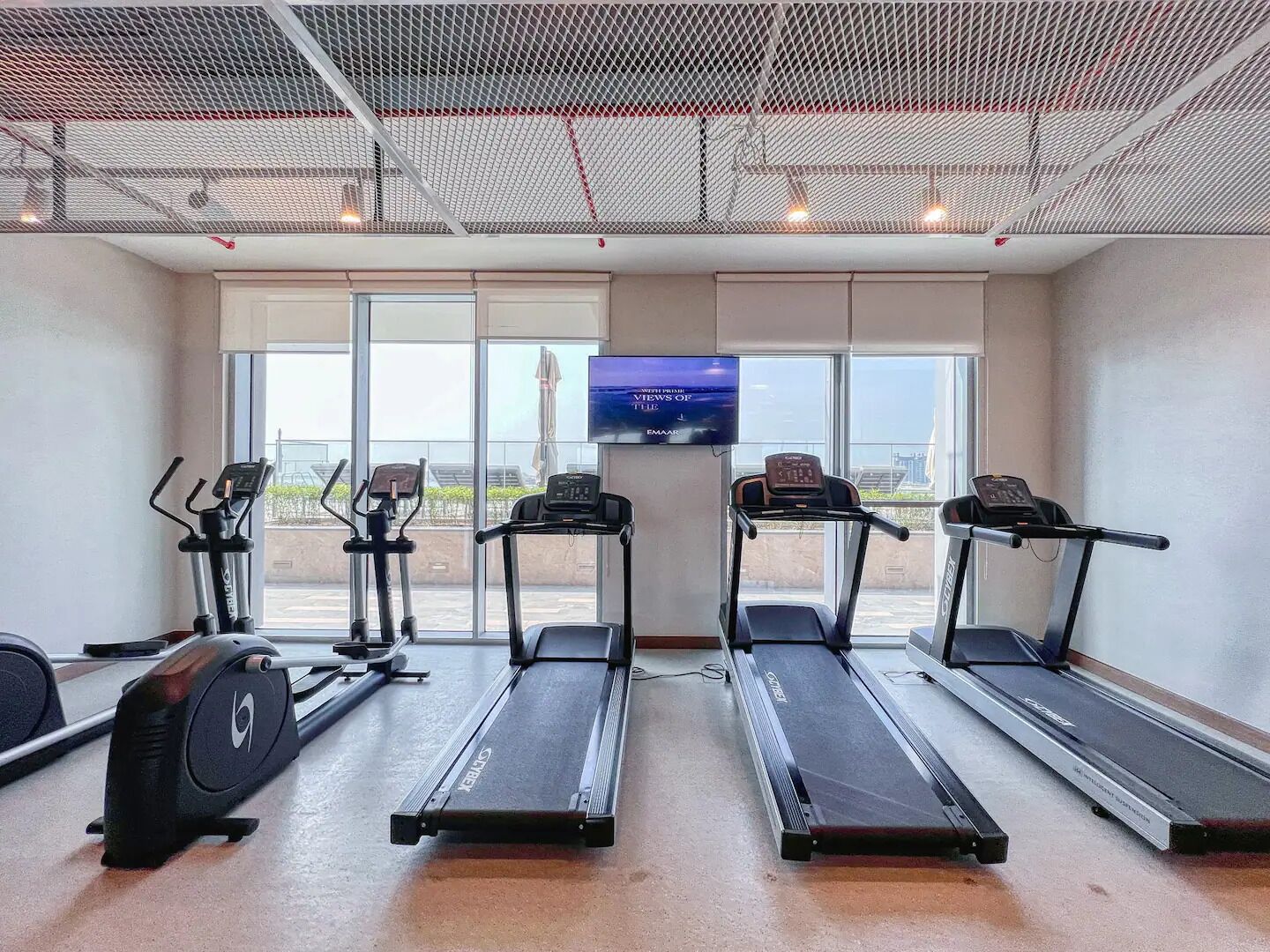 Une salle de sport équipée de tapis de course, de vélos elliptiques et d’un vélo d’appartement.