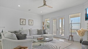 Un salon moderne avec un canapé gris, une table basse en verre et un ventilateur de plafond.