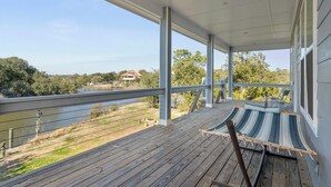 Une terrasse en bois couverte, avec un hamac et des chaises, d’où l’on a vue sur un lac et une maison.