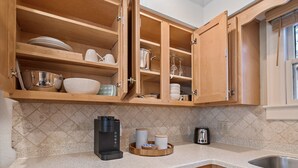 Een keuken met houten kastjes, een koffiezetapparaat, een broodrooster en een spoelbak.