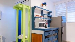 A compact kitchen with a microwave, a refrigerator, and a blue and green cabinet. - Studio #3 Anacaona w/ Garden- Guayacan Guesthouse (Vieques)