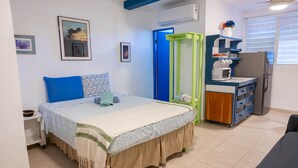 A bedroom with a bed, a small desk, a microwave, and a refrigerator. - Studio #3 Anacaona w/ Garden- Guayacan Guesthouse (Vieques)