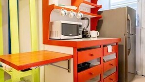 Une cuisine compacte équipée d’un four à micro-ondes, d’une machine à café et d’un réfrigérateur.