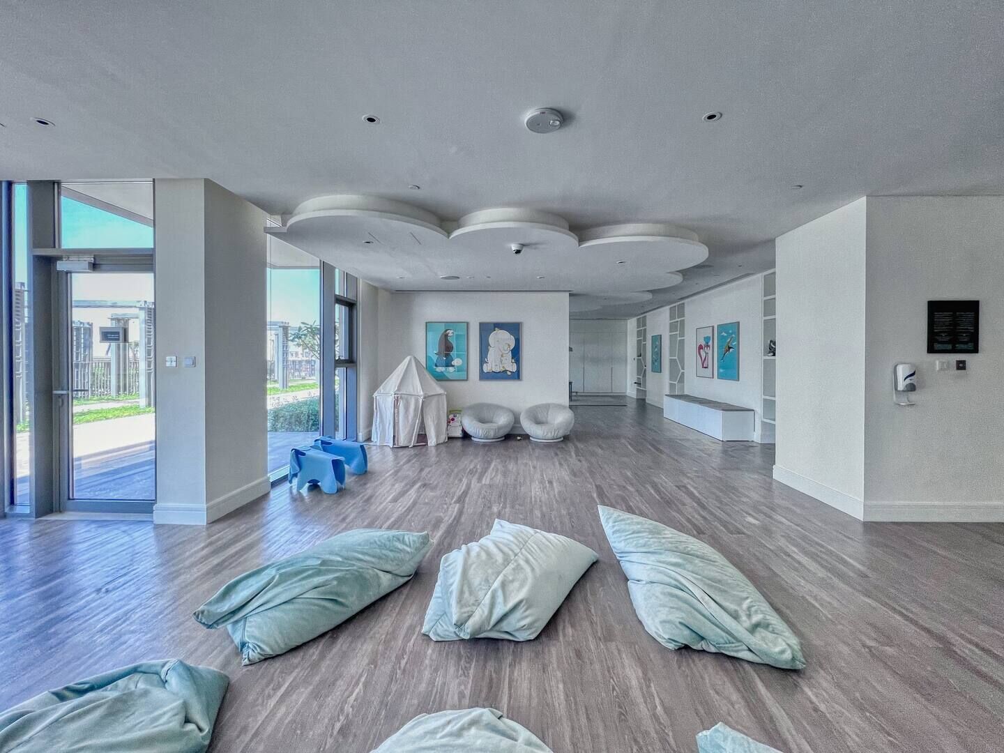 A spacious, modern interior with a high ceiling, large windows, and a view of the outside.