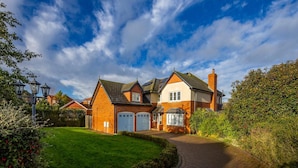 A two-story house with a brick facade, a white garage door, and a well-maintained lawn. - 4 Luxurious Executive Villa (Sheerness)