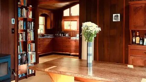 A wooden interior with a kitchen area, a bookshelf, and a vase with flowers on a counter.