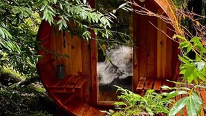 A circular wooden structure with a bench inside, surrounded by greenery.