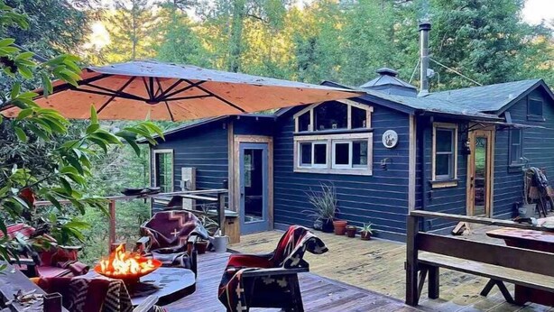 A wooden deck with outdoor furniture, a fire pit, and a covered area with an umbrella.