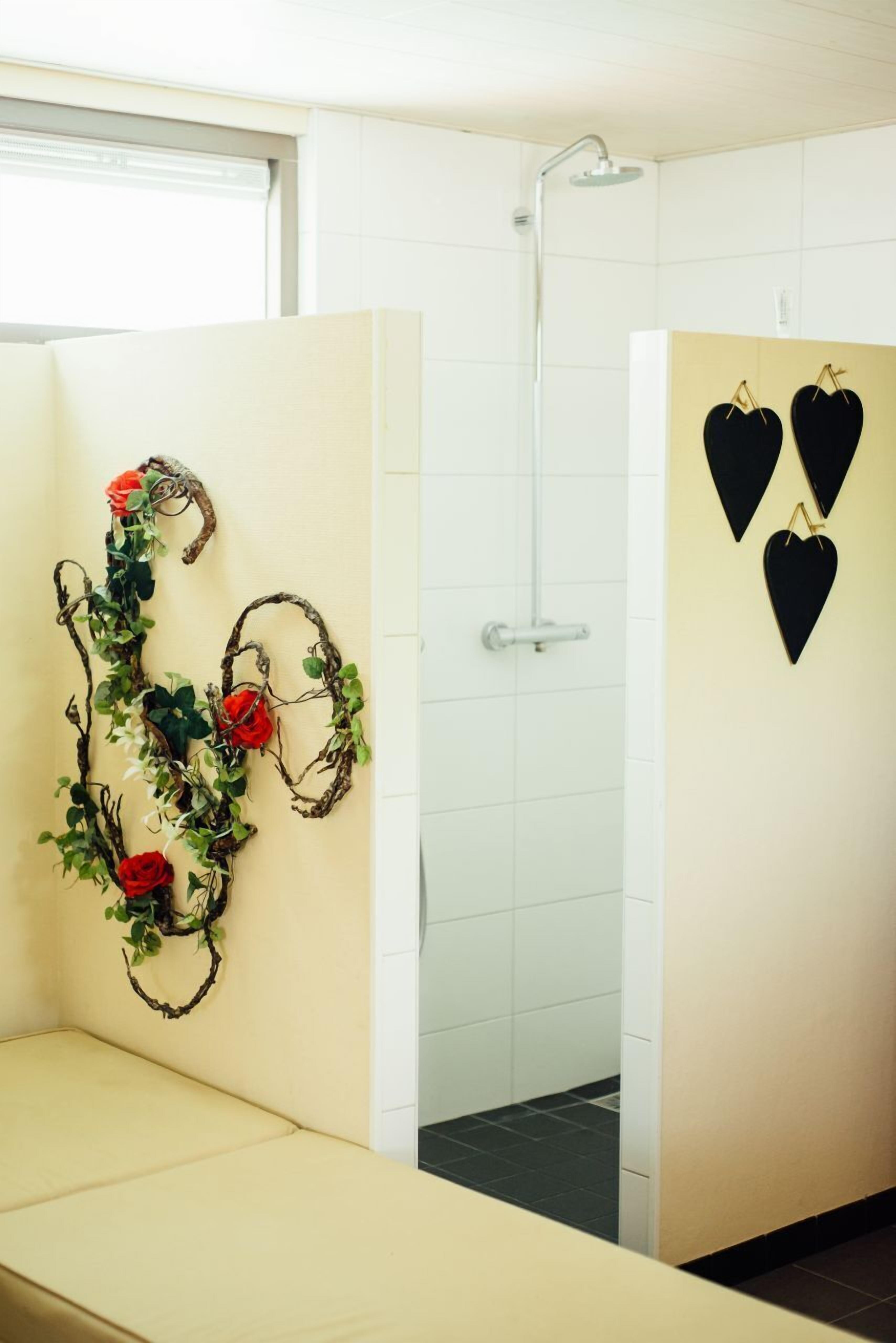 Baño con ducha, banco y detalles decorativos en la pared.