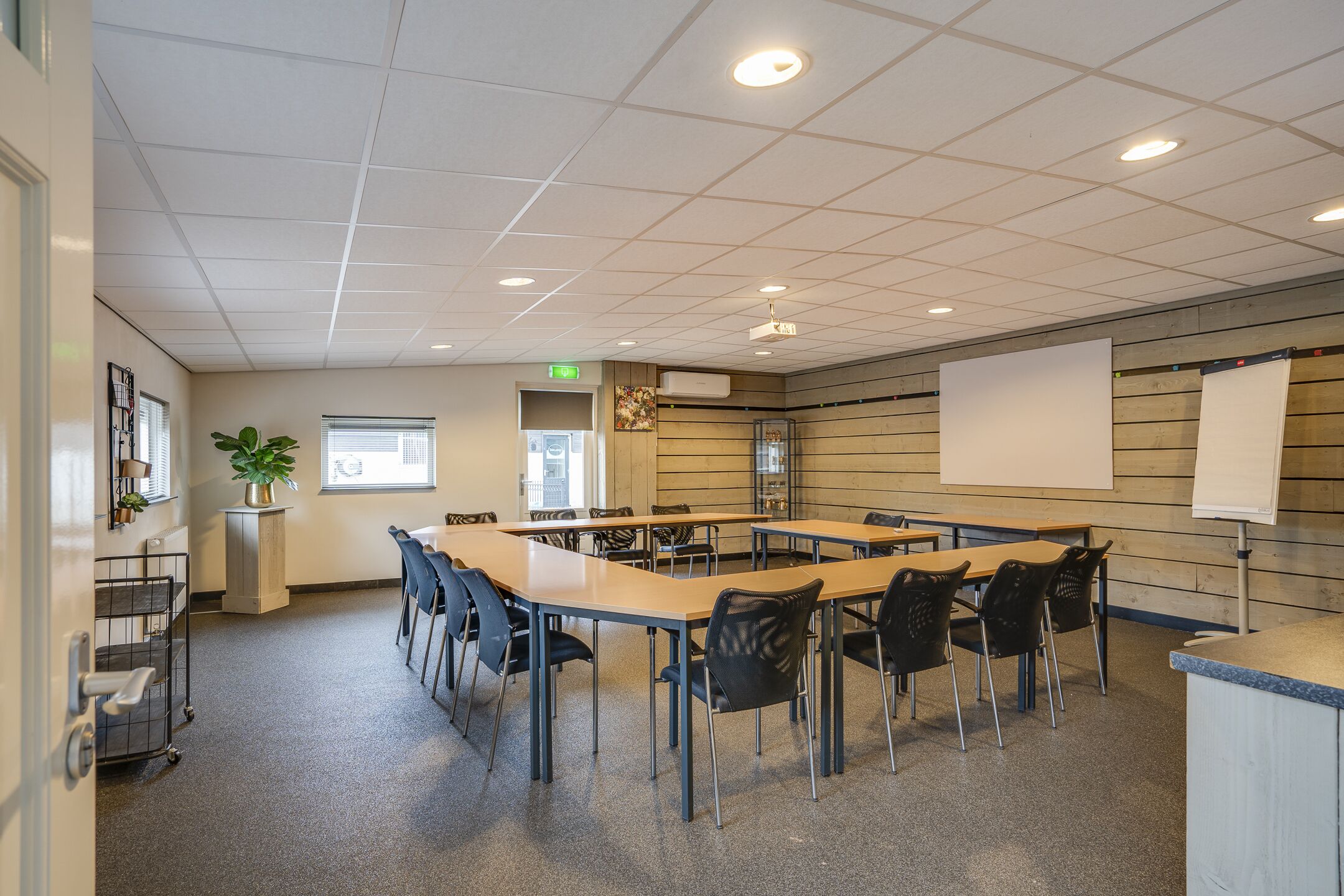 A conference room with a long table, chairs, a whiteboard, and a projector.