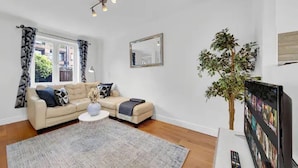 Ein modernes Wohnzimmer mit einem beigefarbenen Sofa, einem Couchtisch und einer großen Pflanze.