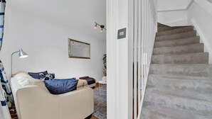 Ein Schlafzimmer mit Bett, Nachttischlampe, kleinem Tisch und einer Vase sowie einer Treppe.