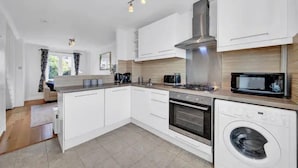 Eine moderne Küche mit weißen Schränken, integriertem Backofen, Mikrowelle und Waschmaschine.