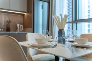 A dining table set with white plates, bowls, and wine glasses, with a vase of white flowers in the center. - 1BR Apartments Beach Isle Tower (Dubai)