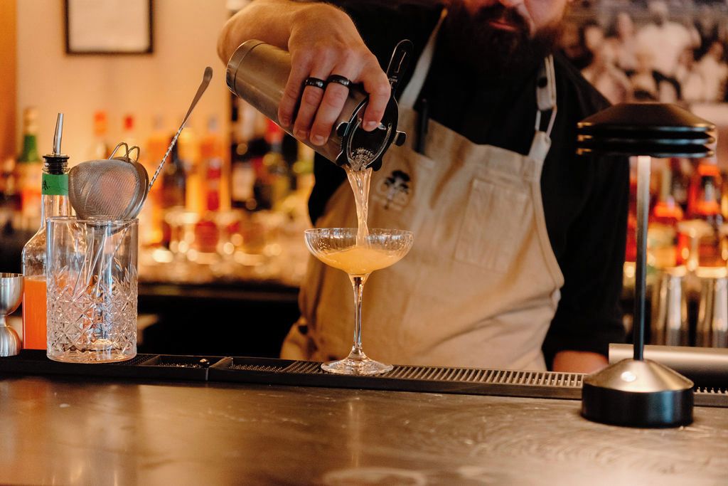Un bartender vertiendo una bebida en un vaso.
