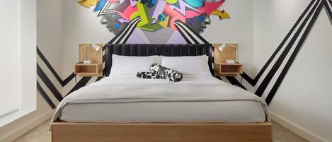 Un dormitorio moderno con una cama de madera, un mural geométrico en la pared y dos mesitas de noche con lámparas.
